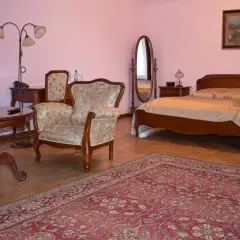 Przytulny pokój w hotelu Skansen Sierpc: łóżko, fotele, stolik i dywan.