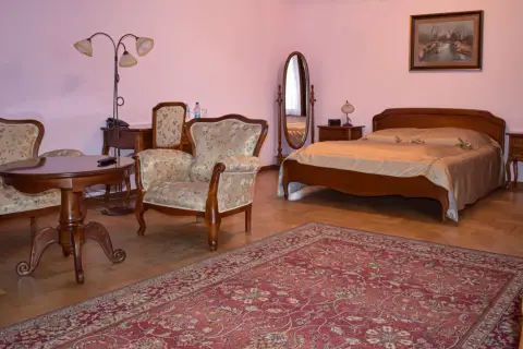 Przytulny pokój w hotelu Skansen Sierpc: łóżko, fotele, stolik i dywan.