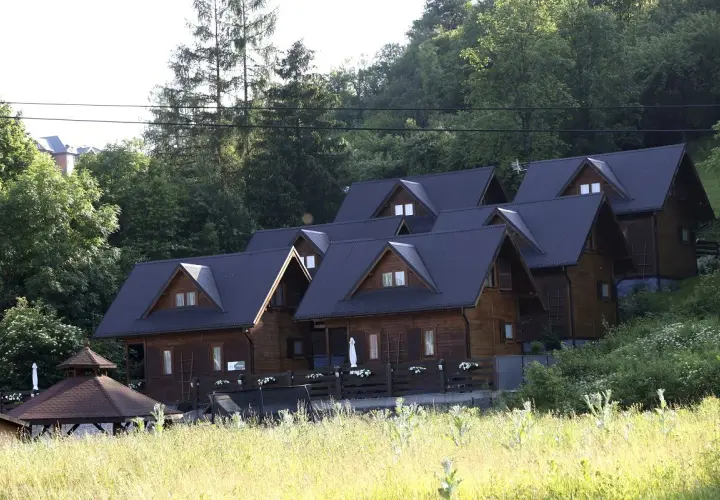 Drewniane domki w górach, idealne miejsce, gdzie szukać noclegu. Otoczone zielenią, z widokiem na las.