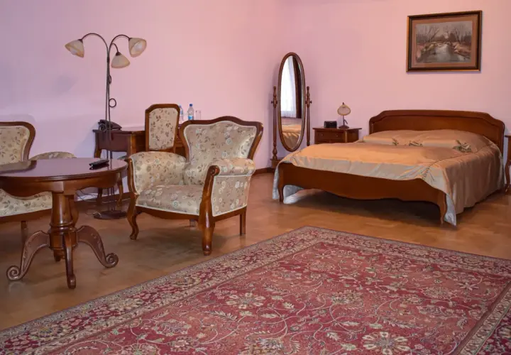 Przytulny pokój w hotelu Skansen Sierpc: łóżko, fotele, stolik i dywan.
