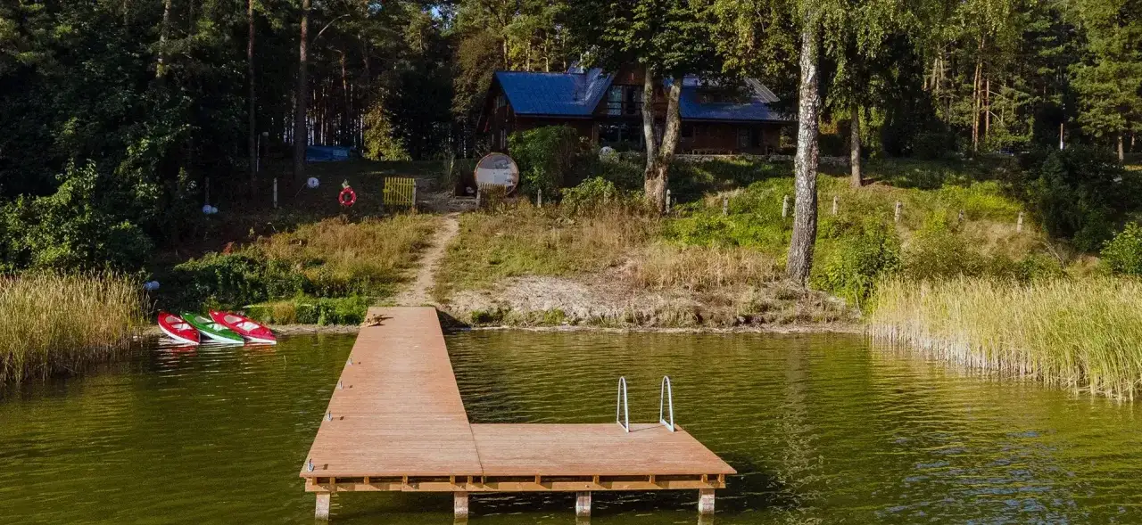 Idealne miejsce, gdzie na ryby z noclegiem Wielkopolska. Drewniane pomosty, kajaki i domek w lesie nad jeziorem.